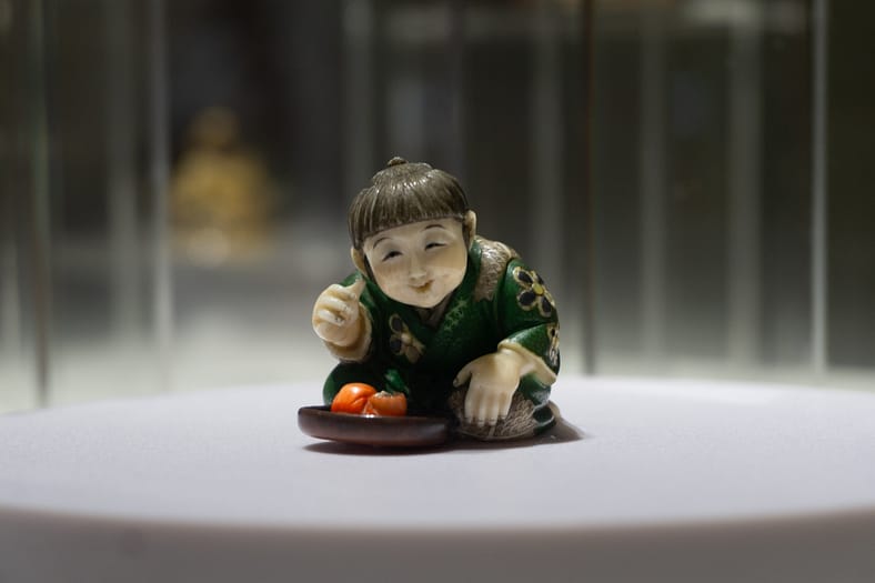 Japanese Netsuke miniature ivory sculpture depicting a boy with a Daruma.